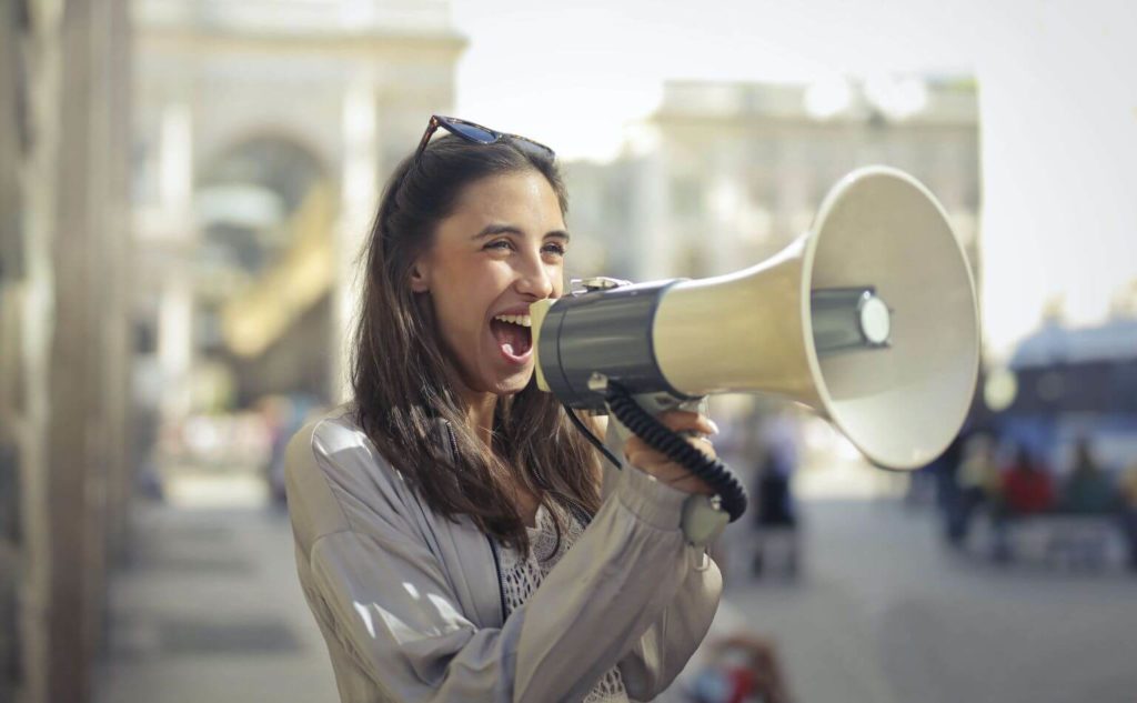 An enthusiastic young woman speaking into a megaphone